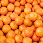 A vibrant close-up of fresh, organic oranges stacked together displaying their freshness and citrus goodness.